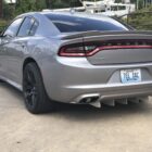Silver Dodge Charger parked, showcasing a rear diffuser and custom black wheels.