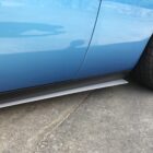 A blue car with a silver side skirt and black wheels parked on a concrete surface.