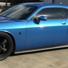 A blue sports car with black wheels parked on a concrete surface.