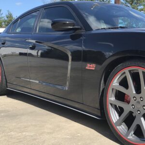 Black car with large silver wheels and red accents parked on a concrete surface.