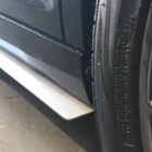 Close-up of a car's side splitter and tire, showcasing the vehicle's design and details.