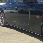 A black car with large silver wheels and red accents parked on a concrete surface.