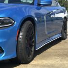 Blue car with black rims parked on a concrete surface, showcasing its sleek design and shiny exterior.