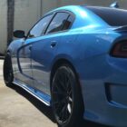 A blue car with black rims parked on a street, showcasing its sleek design and shiny surface.
