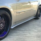 Silver car with large purple-accented wheels and a side skirt on a concrete surface.