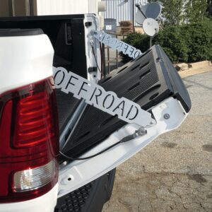 A truck tailgate is open, displaying a black off-road accessory attached to it.