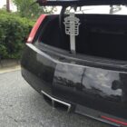 A black car trunk is open, revealing a metal accessory hanging inside.
