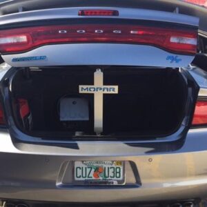 Open trunk of a silver Dodge Charger displaying a Mopar sign and a storage container inside.
