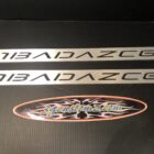 Two metallic car trim pieces with "BAIDAZC6" engraved, alongside a colorful logo sticker.