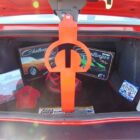 Trunk filled with car memorabilia, including posters, a red hat, and a fire extinguisher. An orange prop is visible.