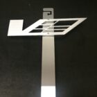 A metallic bracket with a geometric design, featuring a hook for mounting.