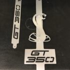 Three metal car emblems labeled "GT 350" and a cobra logo on a dark background.