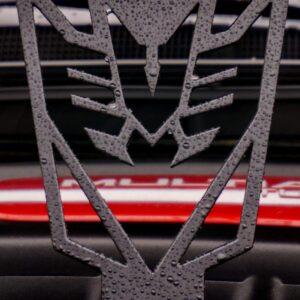 A black, stylized emblem with water droplets, positioned in front of a red background.
