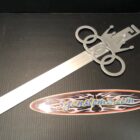 A large, silver sword with a crown and Olympic rings design, next to a colorful logo sticker.