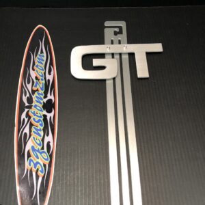 A silver "GT" emblem and a colorful surfboard sticker on a black background.
