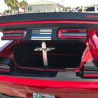 Red sports car trunk open, featuring SRT logo and American flag emblem on the rear.