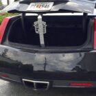 Open trunk of a black car with a decorative item hanging inside.