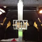 Metal bracket with "FIAT" logo mounted in the trunk of a car, with seats visible in the background.